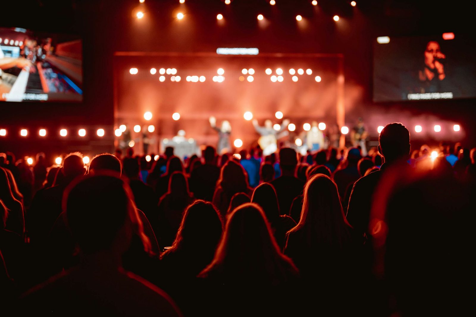 Público em evento com iluminação de palco, ambiente montado pela MS Produções e Eventos