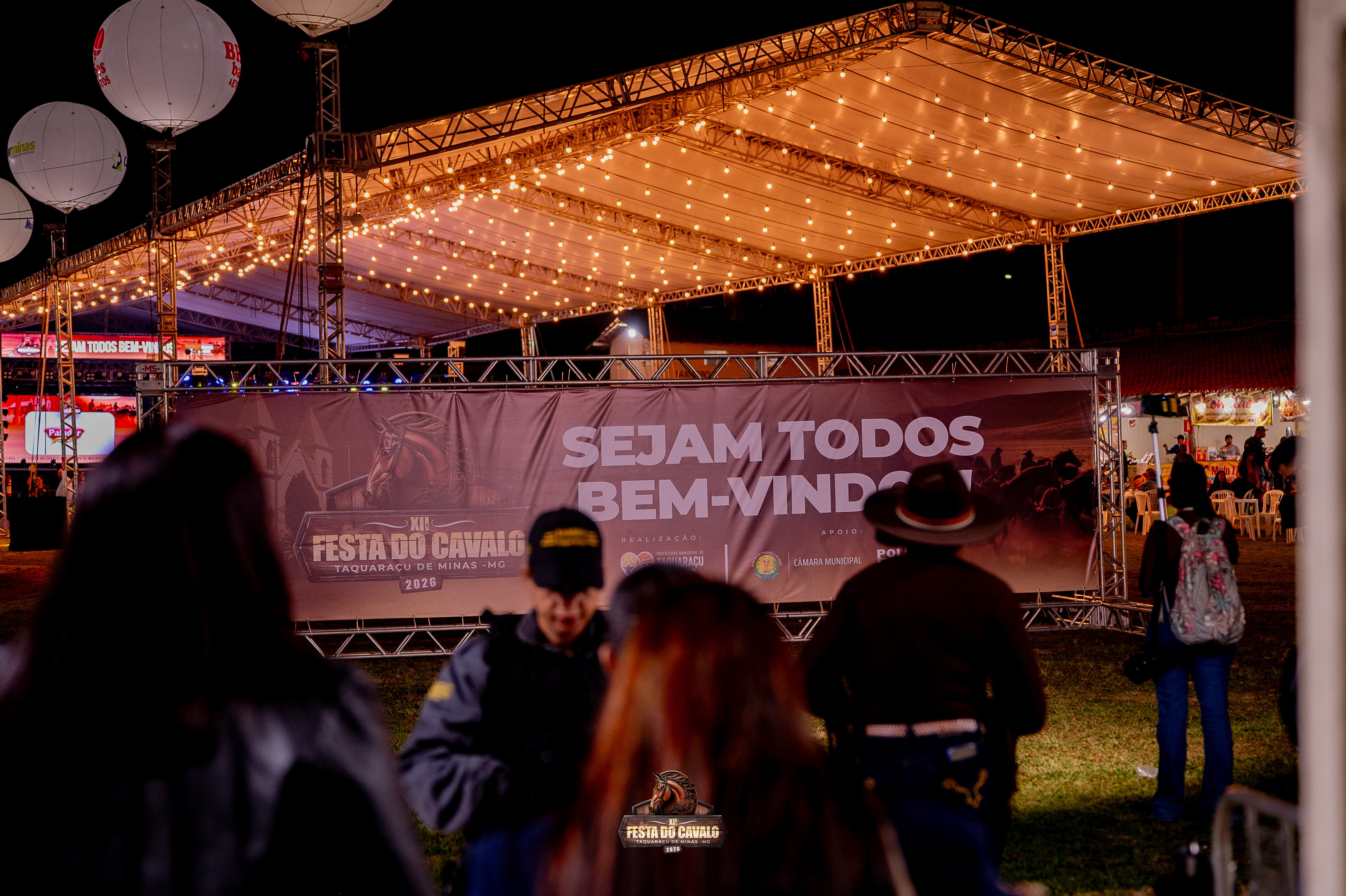 Entrada de evento com tenda iluminada e público