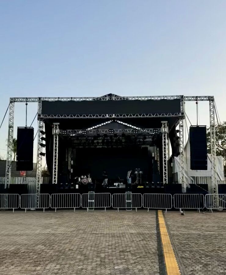 Estrutura de palco montada com grades de contenção de público, durante o dia