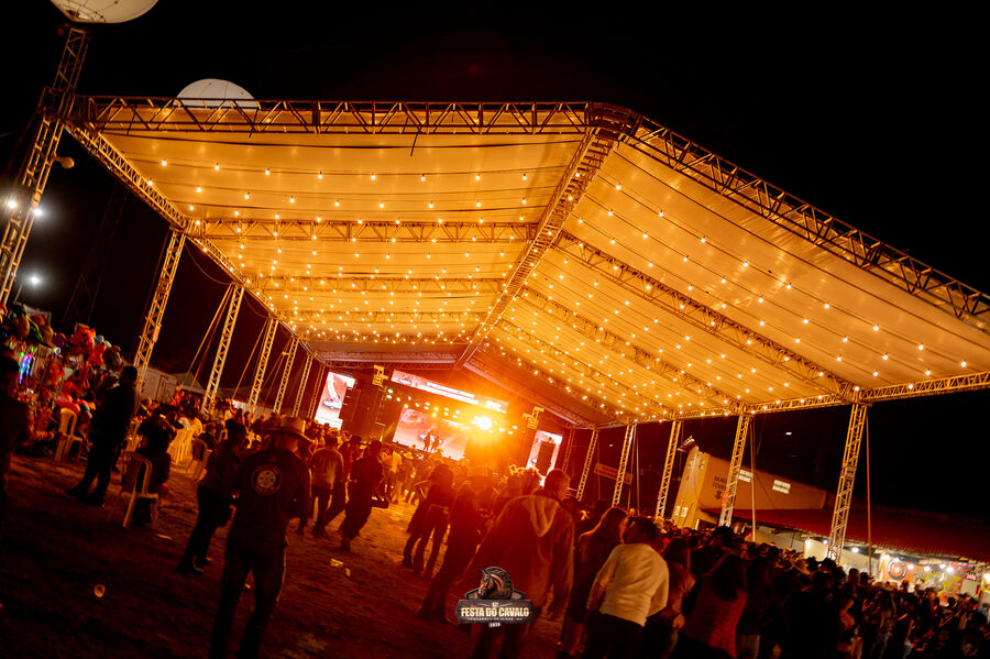 Estrutura de tenda com iluminação decorativa e público em evento