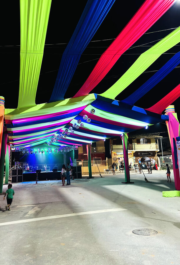 Interior de tenda decorada com tecidos coloridos e iluminação de show